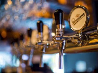 Focused image of a shiny beer tap in a stylish bar with a blurred background.